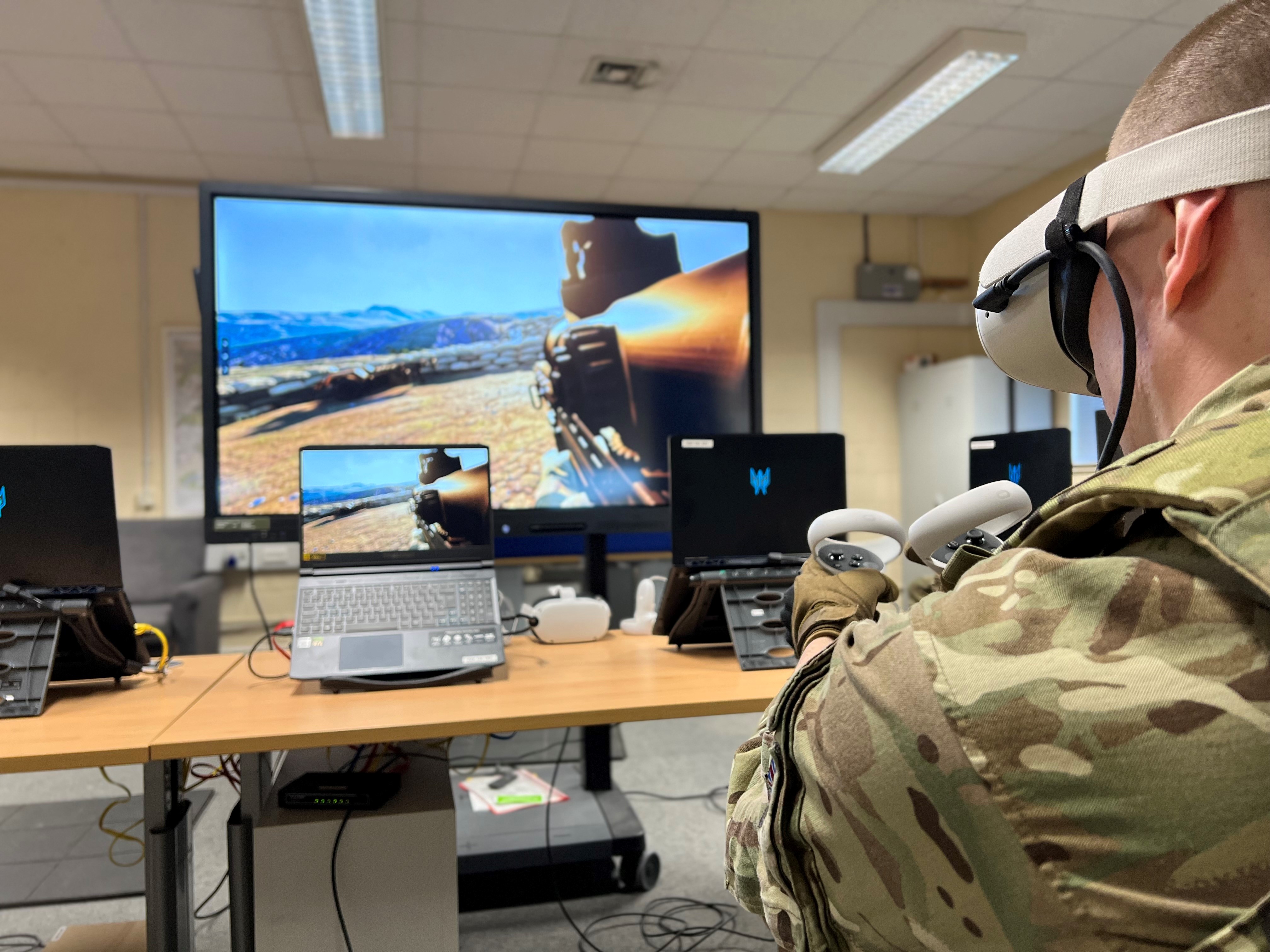 Image shows RAF aviator using virtual reality headset and handset by computers. 
